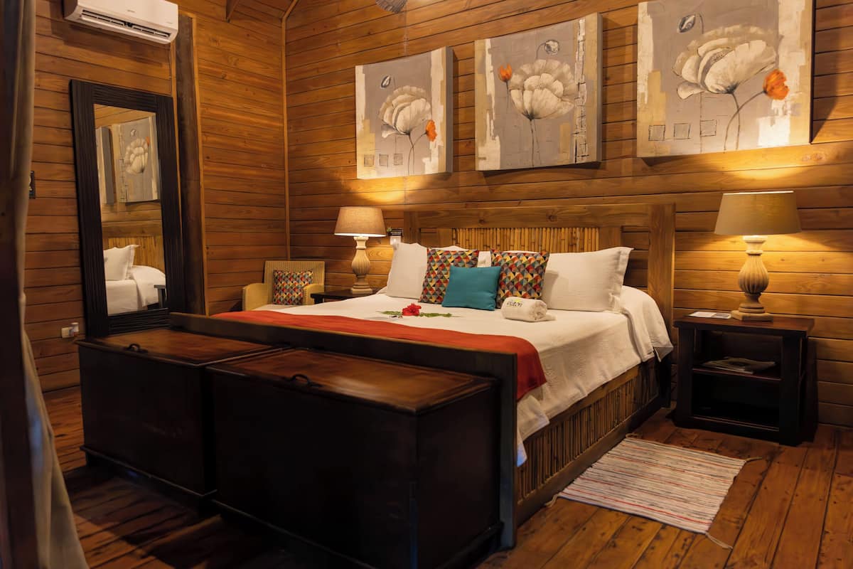Un dormitorio con paneles de madera, una cama, mesitas de noche y obras de arte en las paredes.