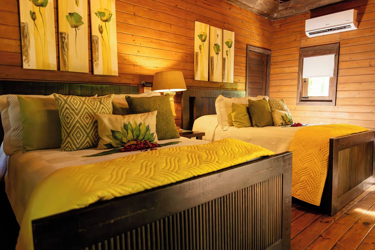 Una habitación con paneles de madera y dos camas, cada una con ropa de cama y almohadas estampadas.