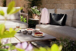 A cozy outdoor seating area with a table set for a meal, a sofa, and a potted plant.