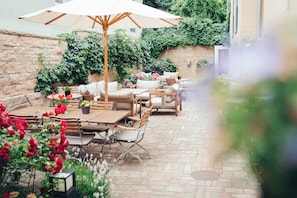 Un patio al aire libre con suelo de piedra, muebles de madera y plantas en macetas.