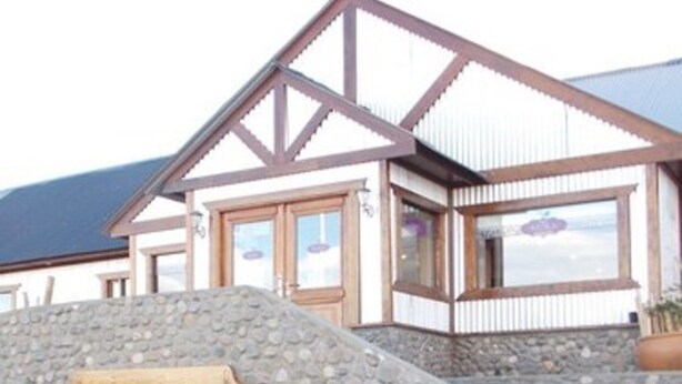 A hotel named "HOTEL MORA" with a stone facade, wooden accents, and a large white vase in the entrance area.