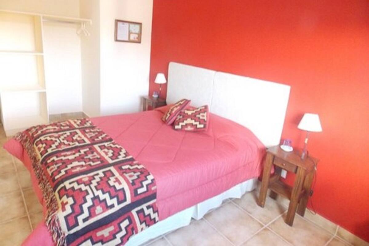 A bedroom with a bed, a nightstand, a lamp, and a wardrobe.