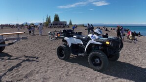 A beach with ATVs, a picnic table, and people.