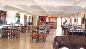 A spacious restaurant with multiple dining areas, a bar, and a seating area with leather sofas.