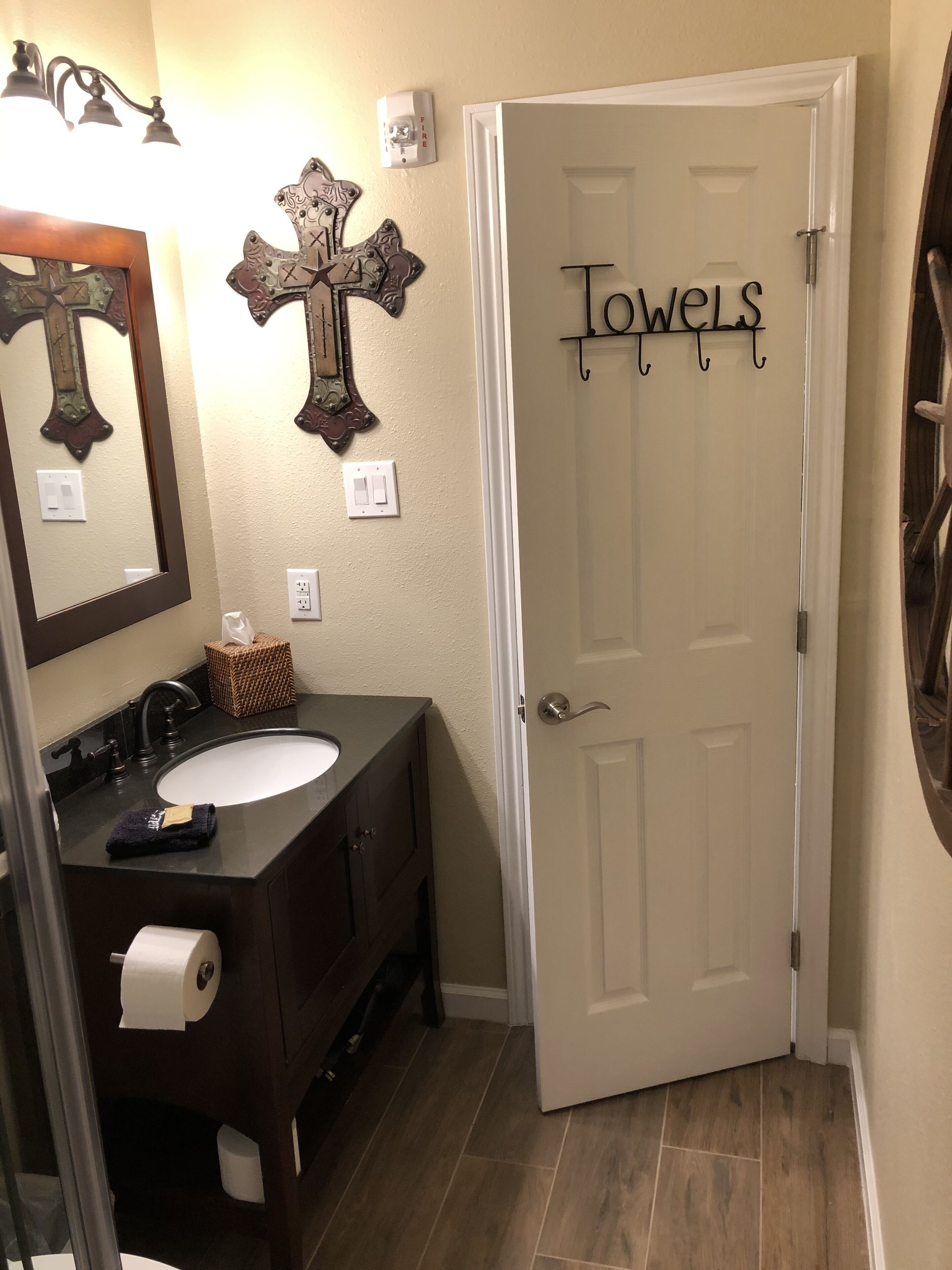 A bathroom with a white sink, dark vanity, and a door with "Towels" sign.