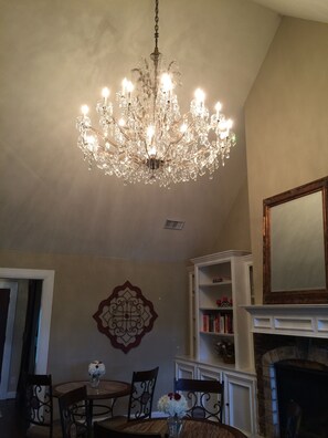 A dining area with a chandelier, a fireplace, and a bookshelf. - Maple Creek Bed and Breakfast (Tomball)