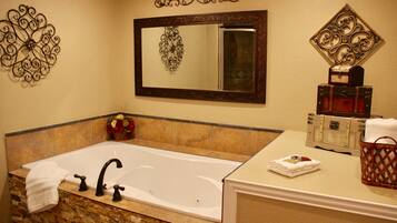 A bathroom with a large bathtub, a vanity with a mirror, and decorative wall art.