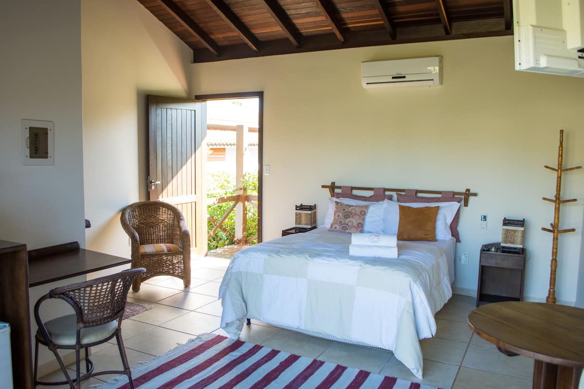 A bedroom with a bed, a chair, a desk, and an air conditioning unit.