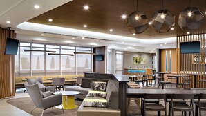 A modern interior with seating areas, tables, and a TV screen. - SpringHill Suites Oklahoma City Midwest City/Del City (Del City)