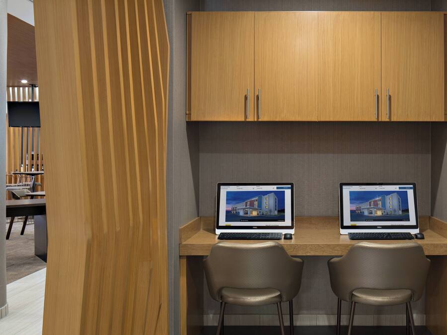 A modern office space with two desks, each with a laptop and a chair.