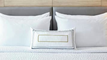 A bed with white bedding and pillows, one with a gold and black border.