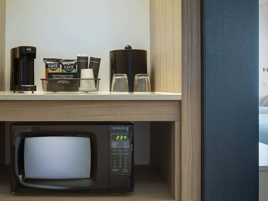 Eine Hotelminibar mit einer Daewoo-Mikrowelle, einer Kaffeemaschine und einem Kaffeeautomaten.