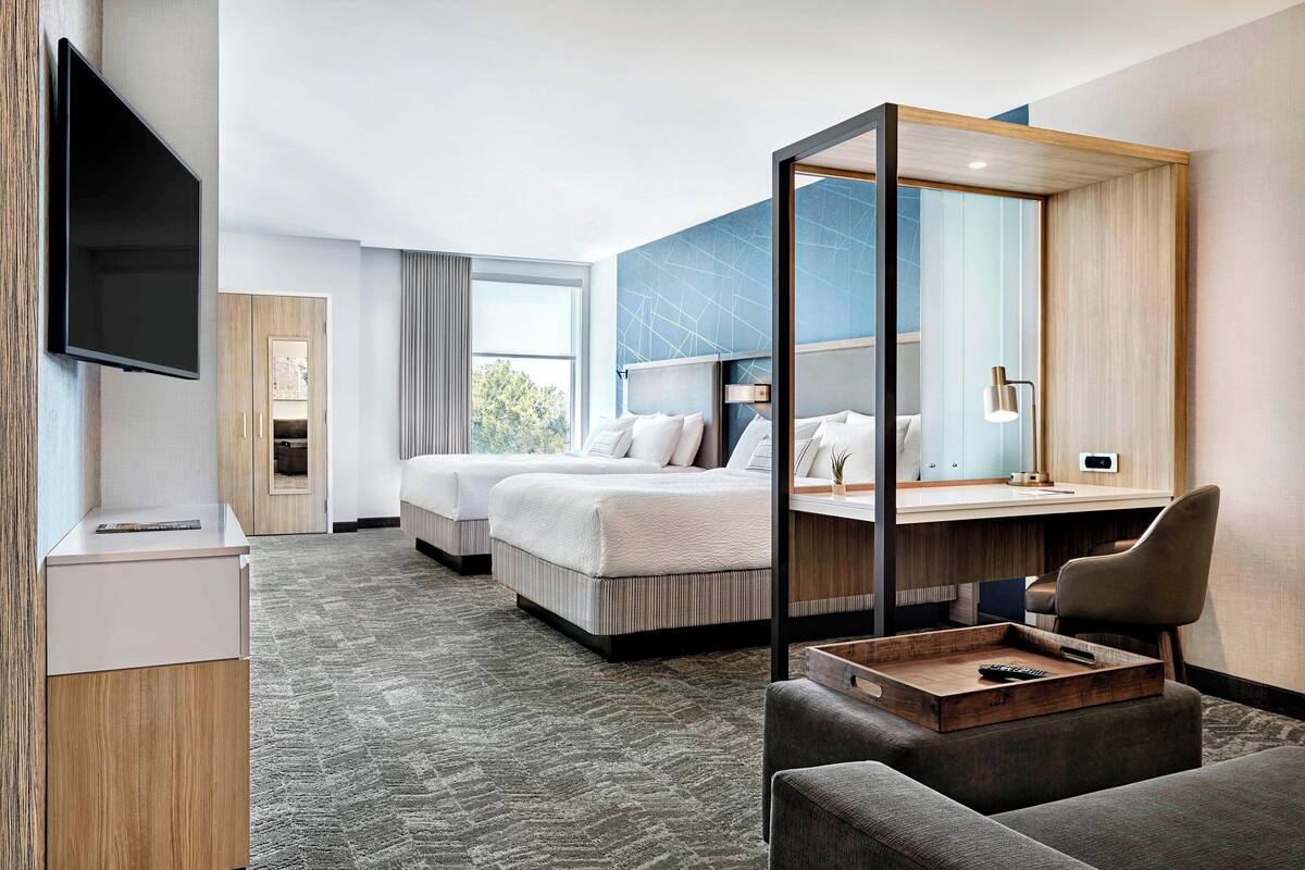 Une chambre d’hôtel avec un grand lit, un bureau, une chaise, une télévision et une fenêtre.