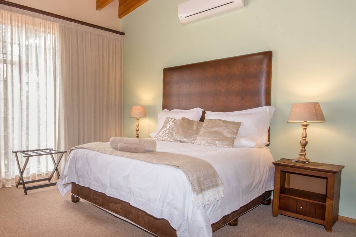 A neatly made bed with a wooden headboard, two bedside lamps, and a small nightstand with a lamp.
