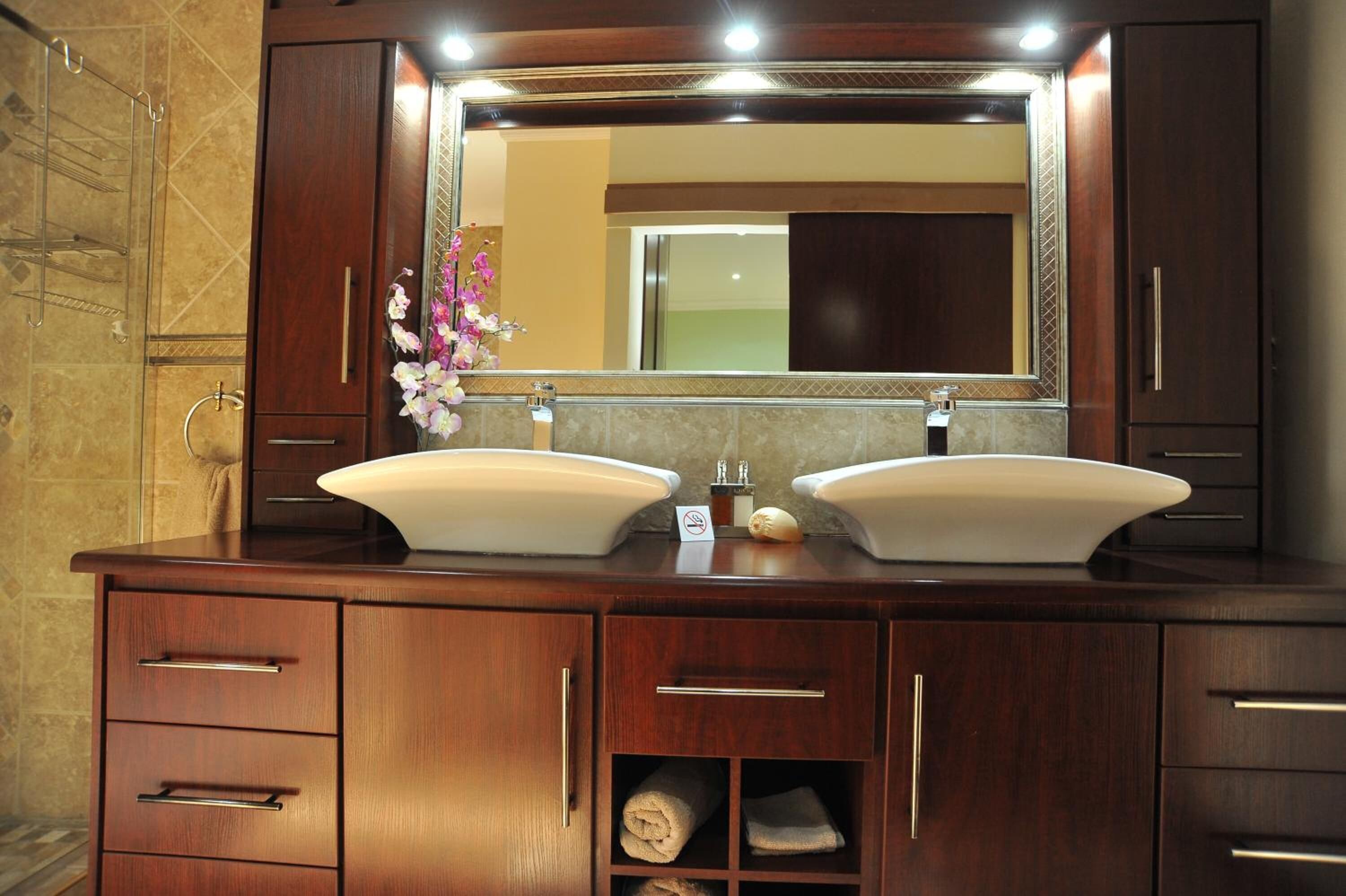 A bathroom with a double sink vanity, a large mirror, and a towel rack.