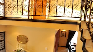 Un interior de varios niveles con una escalera, una zona de comedor con una mesa y sillas, y un cuadro en el nivel superior.