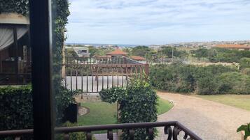 Vista desde un balcón sobre un jardín ajardinado con un sendero pavimentado, un pequeño jardín y edificios a lo lejos.