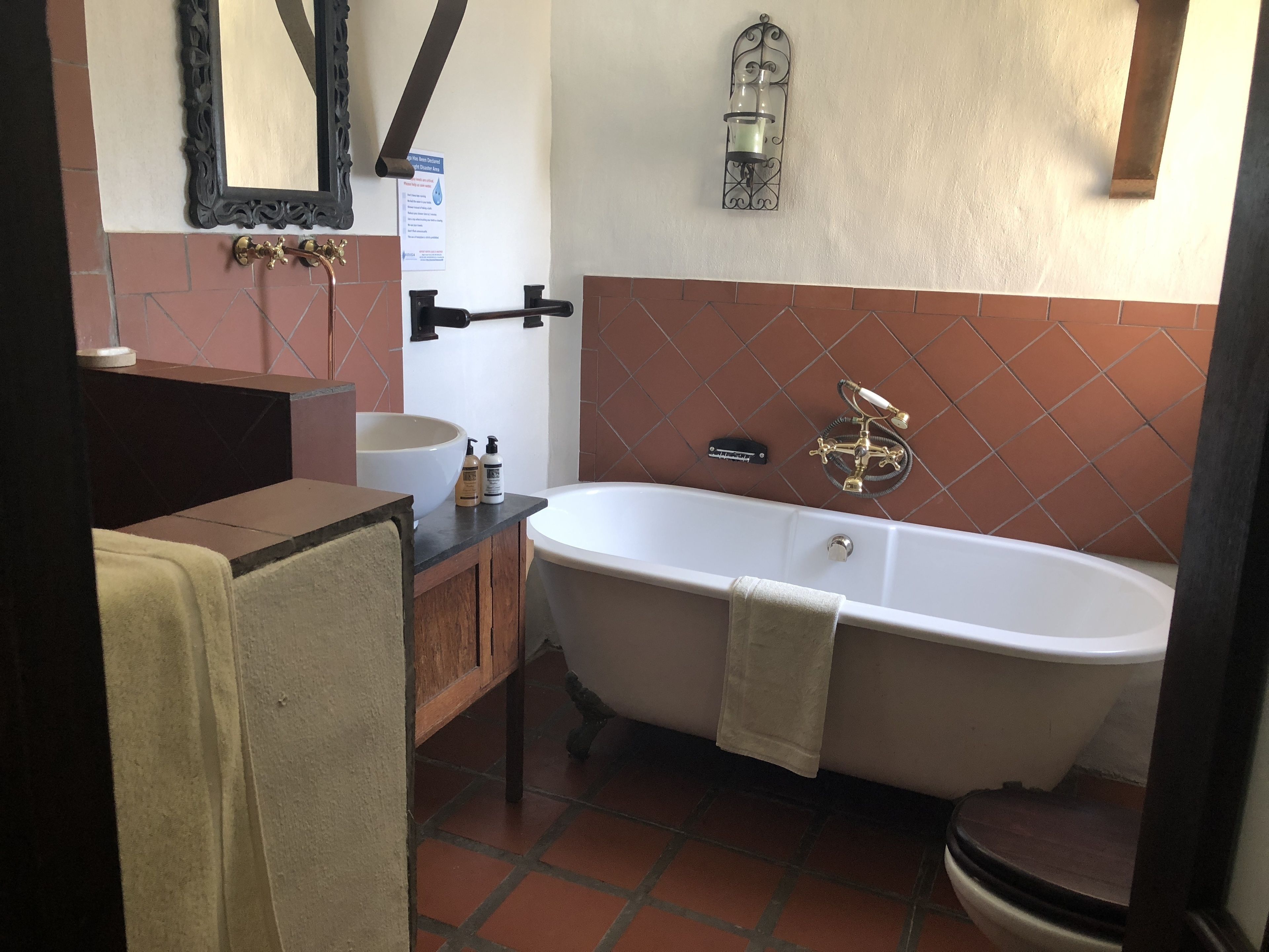 Un bany amb una banyera independent, un lavabo amb mirall i un para-tovallons.