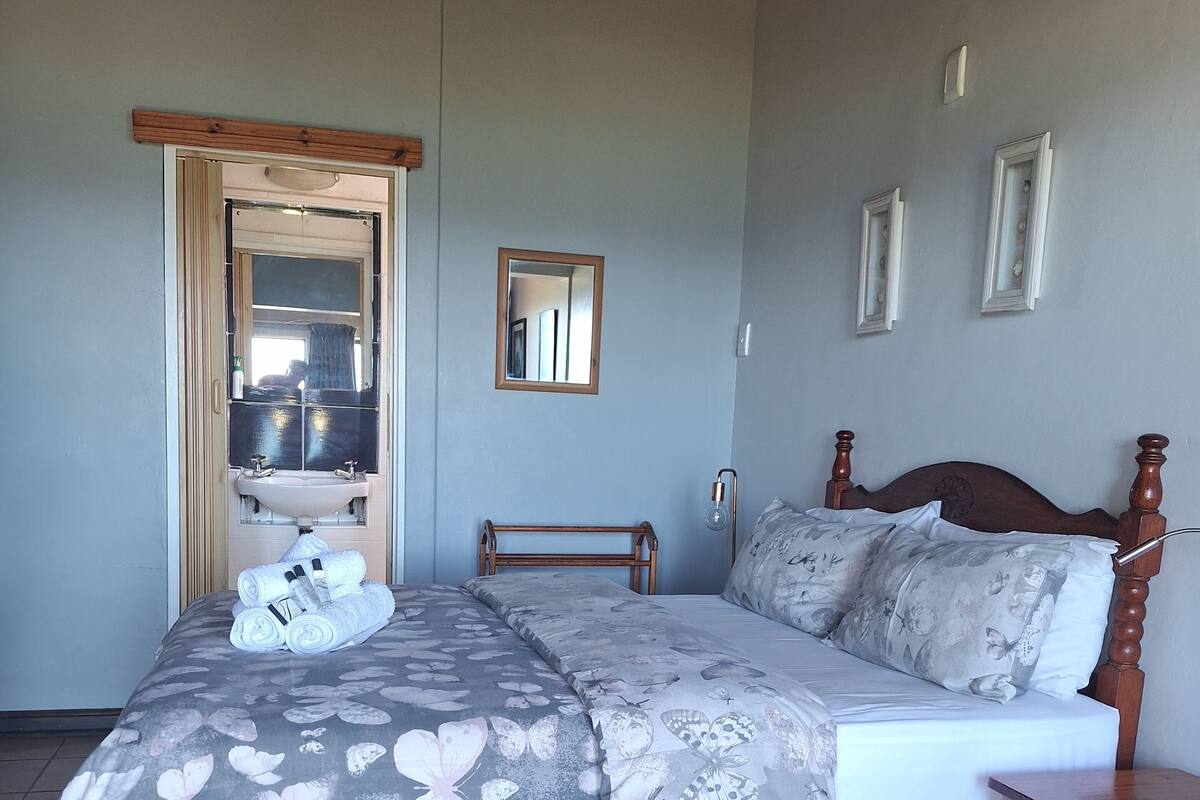 A bedroom with a bed, wooden headboard, a nightstand, a mirror, and a chandelier.