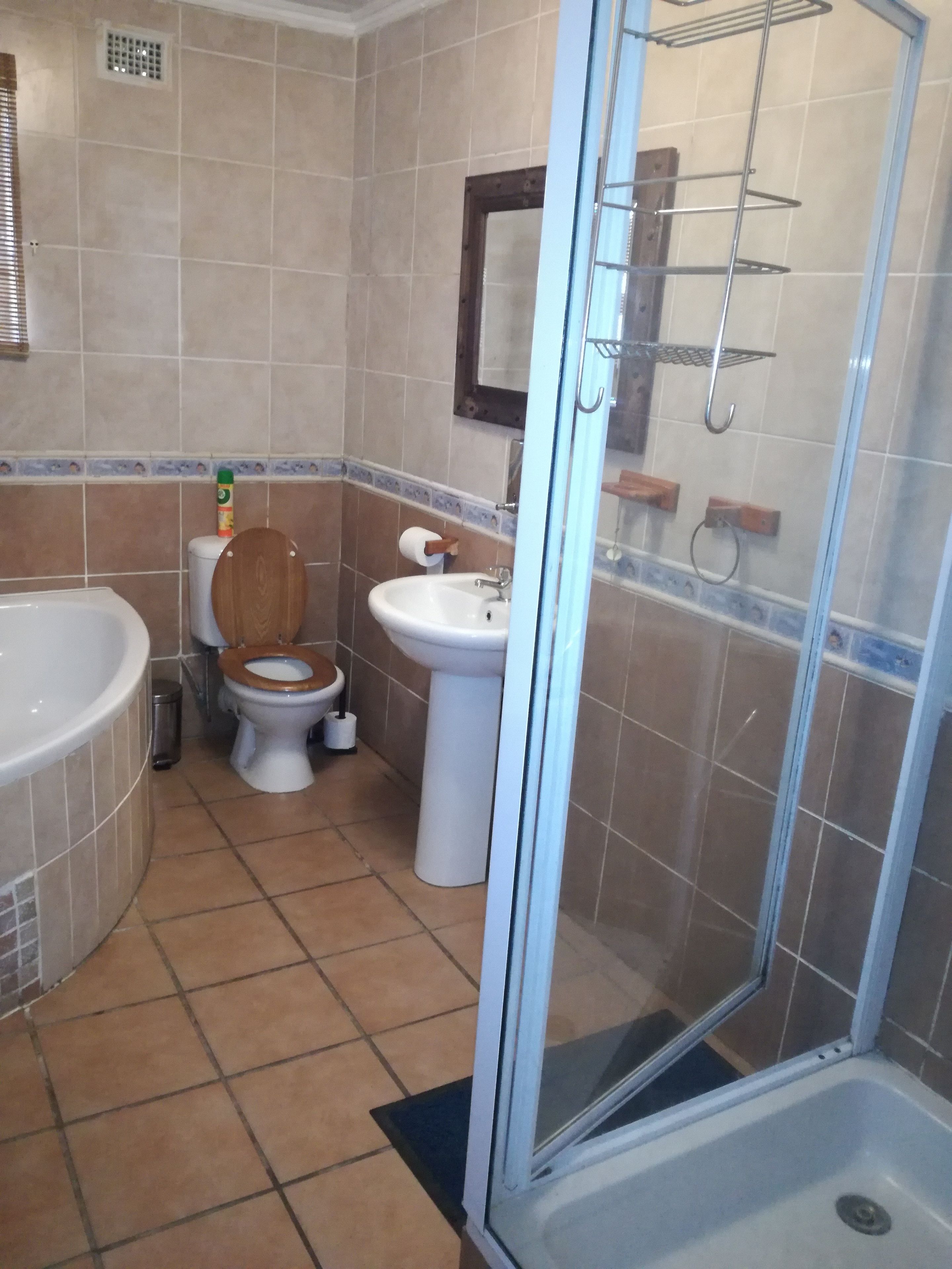 A bathroom with a bathtub, toilet, sink, and glass shower enclosure.