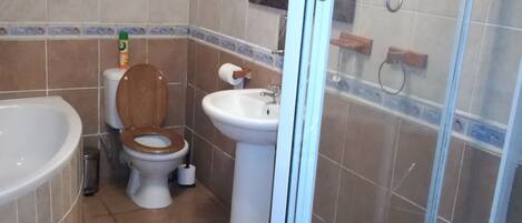 A bathroom with a bathtub, toilet, sink, and glass shower enclosure.