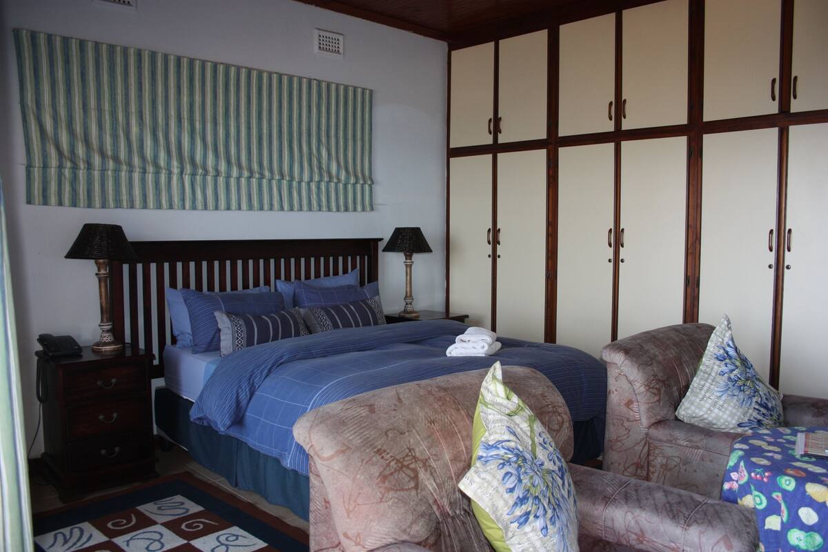 A bedroom with a bed, two nightstands, a wooden wardrobe, and a patterned rug.