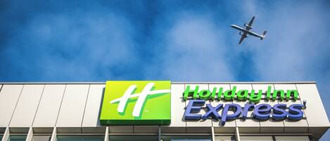 A Holiday Inn Express sign with a clear blue sky and a plane in the background.