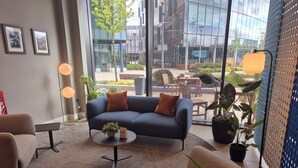 Un espace de bureau moderne comprenant un canapé, des fauteuils, une table basse et des plantes en pot.