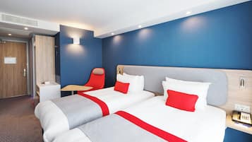A hotel room with two beds, a desk, a chair, and a phone on the nightstand.