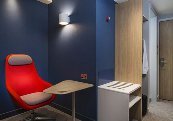 A modern room with a red chair, a small table, and a white cabinet.