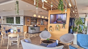 Un espace de détente moderne, doté de sièges, d’un bar et d’un écran de télévision.