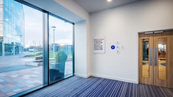 Un vestíbulo de hotel con un amplio ventanal, un cartel en la pared y una recepción.