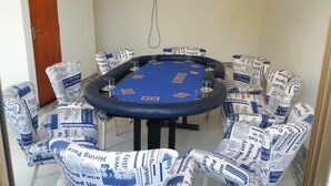 Ein Pokertisch mit Stühlen, die in Zeitungspapier gehüllt sind, eine Tür und eine Wand.