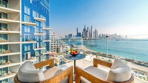 Een balkon met een tafel waarop fruit staat, met uitzicht op een stadsbeeld en een strand.