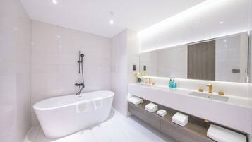 Un baño moderno con una bañera independiente, un espejo grande y un tocador con lavabo y toallero.
