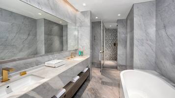 Un bagno moderno con pareti in marmo, un grande specchio, un mobile lavabo doppio, una vasca da bagno e uno spazio doccia.
