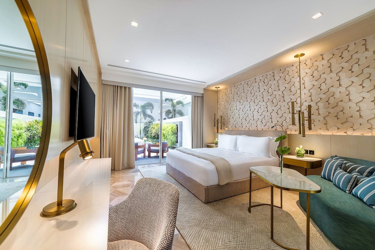 A modern hotel room with a large bed, a sofa, a small table, and a TV.