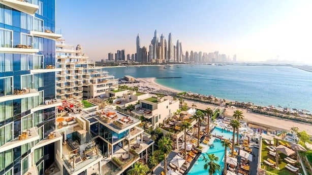 Een hoog hotel met meerdere balkons met uitzicht op een strand en een stadsbeeld.