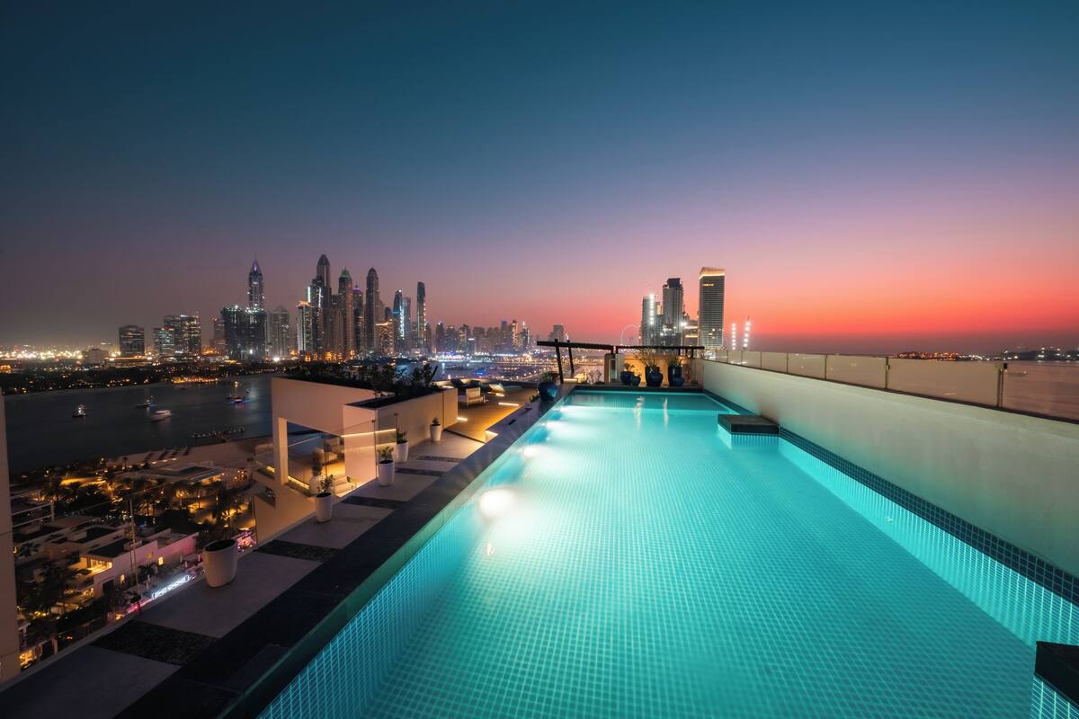 A rooftop infinity pool with a city skyline view at sunset.
