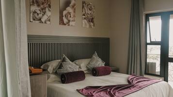 A bedroom with a bed, pillows, a blanket, and wall art.