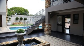 Un espace extérieur moderne doté d’une piscine, d’un escalier en pierre et d’un petit élément décoratif aquatique.