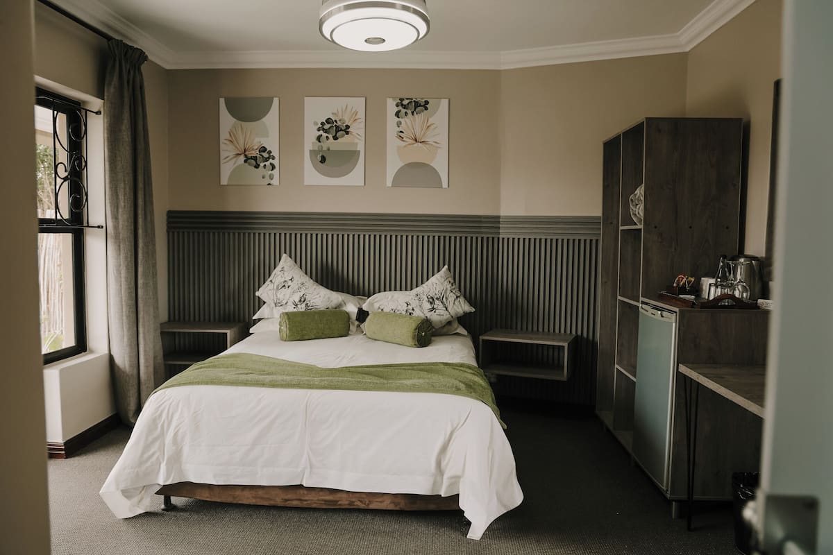 A neatly arranged bedroom with a bed, bedside tables, a wardrobe, and artwork on the wall.