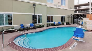 Una piscina al aire libre, sombrillas, sillones reclinables de piscina