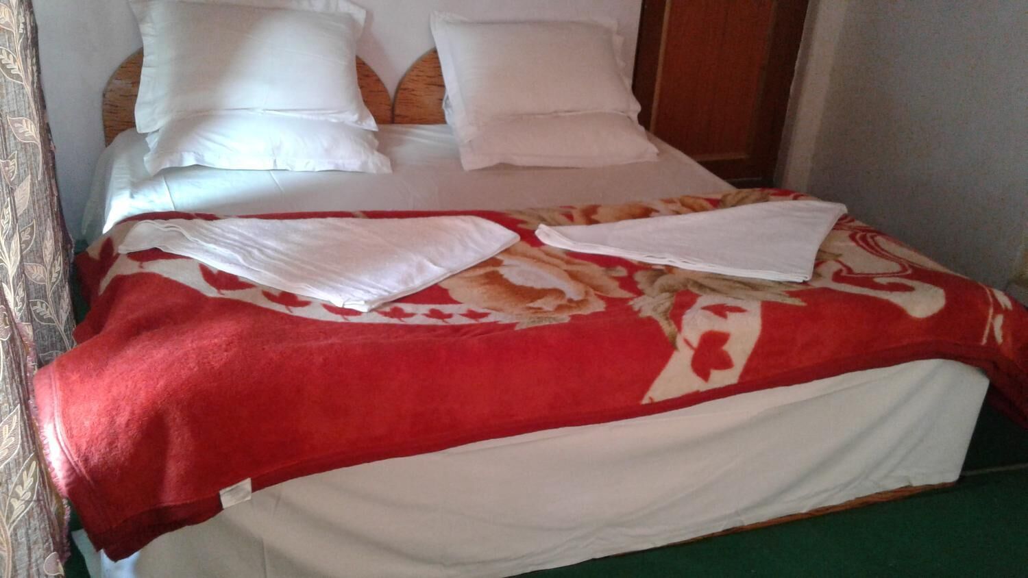 A bed with white bedding and a red and white patterned blanket.