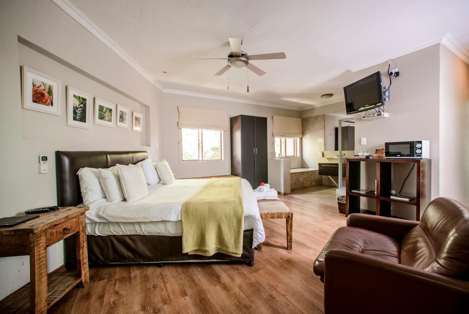A bedroom with a bed, bedside table, TV, and a wooden floor.