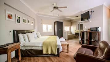 A bedroom with a bed, bedside table, TV, and a wooden floor.