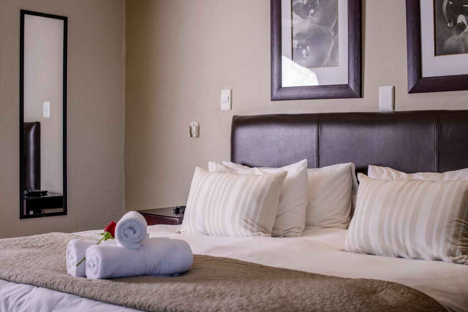 Una camera d'albergo con un letto grande, una testiera e due quadri appesi al muro.