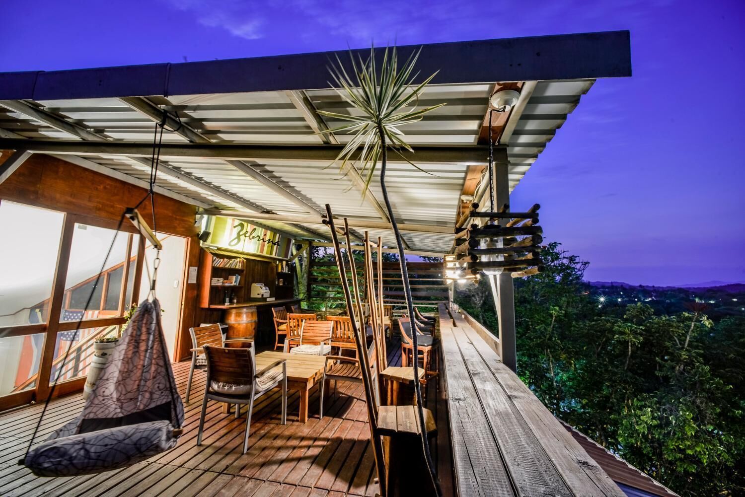 A wooden deck with outdoor seating, a bar area, and a view of the surrounding landscape.