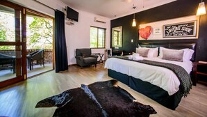 Un dormitorio con cama, una silla, una mesa, un televisor y vistas al exterior.
