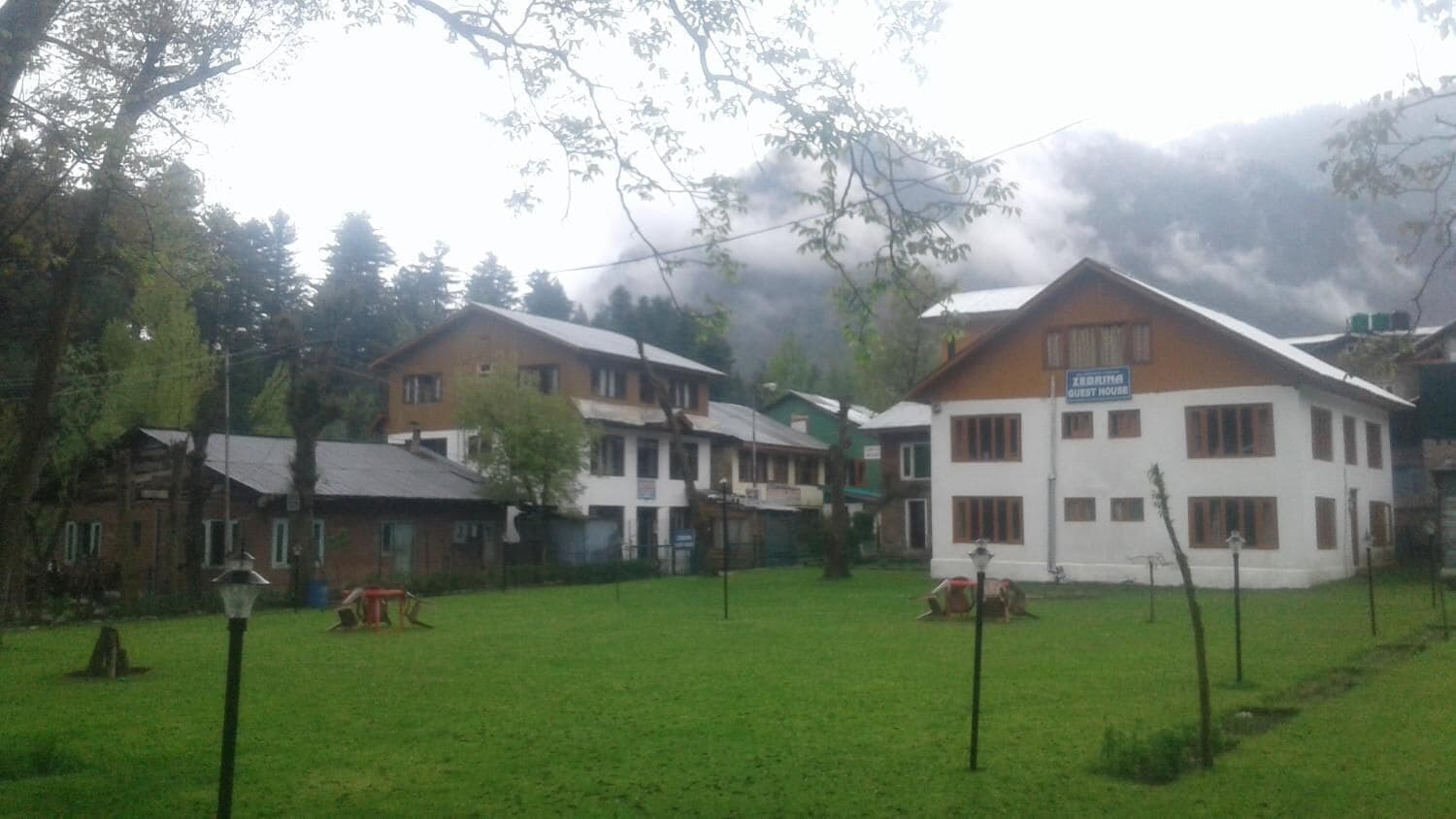 A guest house with a sign indicating its purpose, surrounded by a green lawn and trees.